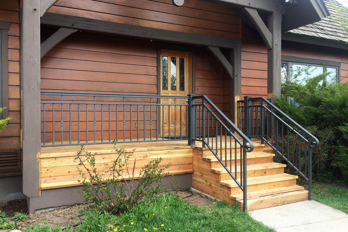 Wooden deck with metal railing leading to a house entrance